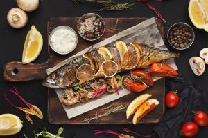 Grilled fish on a wooden board at a restaurant table in Istria, showcasing local cuisine.