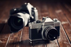 Vintage camera and modern camera on a wooden surface.