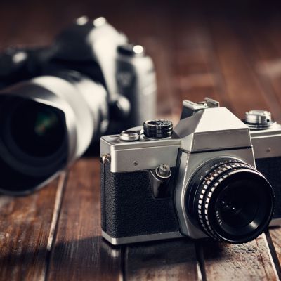 Vintage camera and modern camera on a wooden surface.