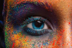 Close-up of a female eye with colorful and creative art makeup, inspired by abstract splashes.