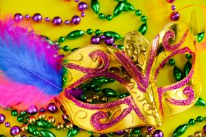 Carnival mask with feathers on a yellow background.