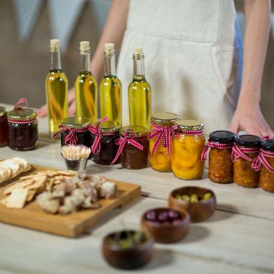 Jars of preserves and bottles of olive oil on a table at a food festival.