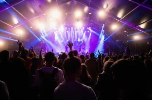 Foule à un concert d'un festival de musique d'été avec des lumières de scène et de la fumée.