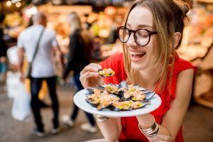 A woman eating mussels at a food festival.