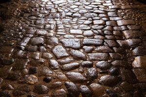 Close-up of ancient Roman cobblestone street, glistening in the light