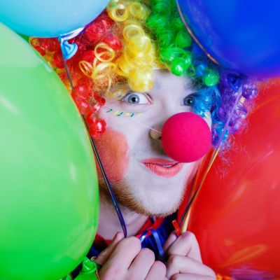 Colorful clown holding balloons at a circus festival